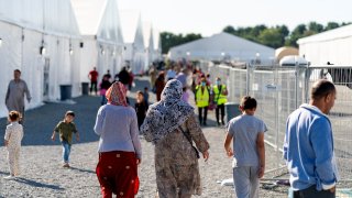 FILE - Afghan refugees walk through an Afghan refugee camp at Joint Base McGuire Dix Lakehurst, N.J., on Sept. 27, 2021.