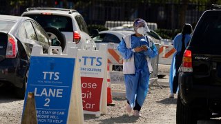 FILE - Workers wear protective equipment at a COVID-19 testing site on Jan. 26, 2022, in the Boyle Heights section of Los Angeles.