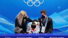 Kamila Valieva of Team ROC reacts to her score with choreographer Daniil Gleikhengau, right, and coach Eteri Tutberidze, left, after the Women's Free Skate event at the 2022 Winter Olympic Games, Feb. 17, 2022, in Beijing.