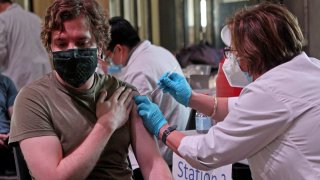 Nathan Jacobs, of Boston gets his Covid Booster shot from Sassy Yogurtian at City Hall on December 9, 2021 in, in Boston, MA.