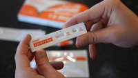 A Walmart worker in Provo, Utah, shows she tested negative using a government-issued Covid-19 Antigen Rapid test kits she received on Feb. 8, 2022.