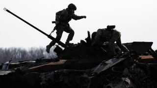 A Ukrainian serviceman walks on a destroyed Russian fighting vehicle in Bucha, Ukraine, Thursday, April 7, 2022. Russian troops left behind crushed buildings, streets littered with destroyed cars and residents in dire need of food and other aid in a northern Ukrainian city, giving fuel to Kyiv's calls Thursday for more Western support to help halt Moscow's offensive before it refocuses on the country's east.