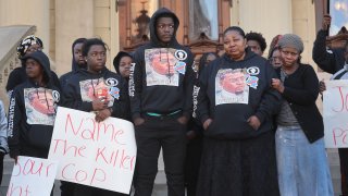 Supporters and family members of Patrick Lyoya, including his mother Dorcas Lyoya (2nd from R), listen to speakers during a rally in front of the Michigan state capital building where demonstrators were calling on the Grand Rapids police department to name, arrest and prosecute the officer that shot Patrick