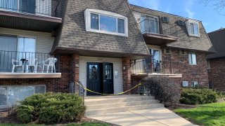 A three-story apartment building, with yellow police tape in front of the front door, is seen after a shooting in Elgin on April 10