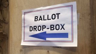 A sign reads "ballot drop-box" an arrow underneath points left.