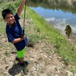 Jose Flores holding a fishing rod with a fish on the line.