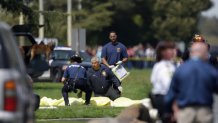 Emergency responders kneel by bodies covered