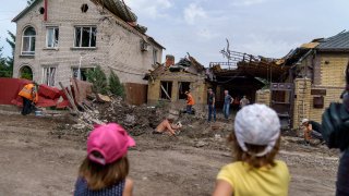 Children watch as workers clean up after a rocket strike on a house in Kramatorsk, Donetsk region, eastern Ukraine