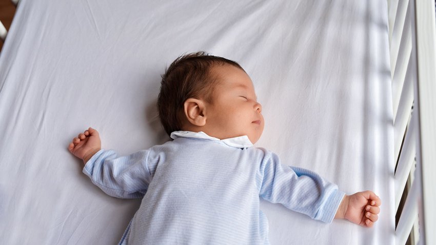 baby girl sleeping in crib seen from above