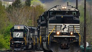 A Norfolk Southern freight train passes a train on a siding as it approaches a crossing in Homestead, Pa., Wednesday, April 27, 2022.