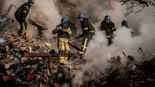 Ukrainian firefighters works on a destroyed building after a drone attack in Kyiv on October 17, 2022.