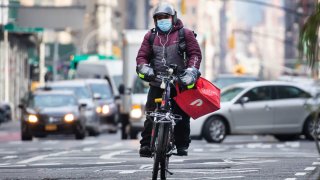 A bike messenger carries a DoorDash bag during a delivery in New York, Wednesday, Dec. 9, 2020.
