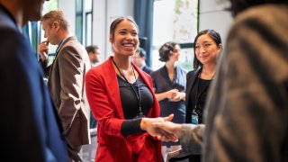 Businesswomen handshaking in auditorium corridor