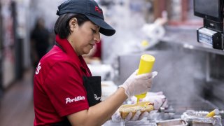 An employee prepares a hot dog at a Portillo’s restaurant in Chicago, Illinois, on Tuesday, Sept. 27, 2022.