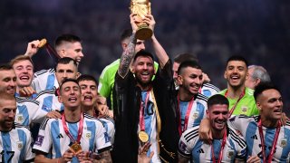 Argentina’s captain and forward #10 Lionel Messi (C) lifts the FIFA World Cup Trophy on stage as he celebrates with teammates after they won the Qatar 2022 World Cup final football match between Argentina and France at Lusail Stadium in Lusail, north of Doha on December 18, 2022.