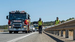 In this photo provided by the Department of Fire and Emergency Services, its members search for a radioactive capsule believed to have fallen off a truck being transported on a freight route