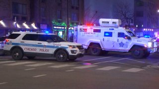 Two Chicago police vehicles, an SUV with red, white and blue lettering in the foreground and a SWAT armored vehicle in the background, are seen near the scene of a carjacking in Old Town.