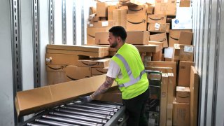A worker loads customer orders into a waiting tractor-trailer inside the million-square foot Amazon distribution warehouse that opened last fall in Fall River, MA on Mar. 23, 2017.