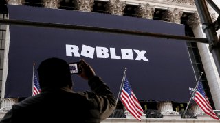 A man photographs a Roblox banner displayed, to celebrate the company’s IPO, on the front facade of the New York Stock Exchange (NYSE) in New York, March 10, 2021.