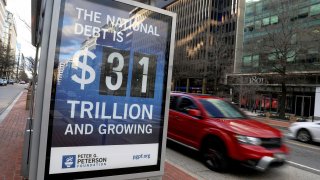 A car drives next to a board at a bus stop showing a U.S. national debt figure after the U.S. government hit its $31.4 trillion borrowing limit amid a standoff between the Republican-controlled House of Representatives, President Joe Biden and Democratic legislators that could lead to a fiscal crisis in a few months, in Washington, U.S., January 20, 2023.