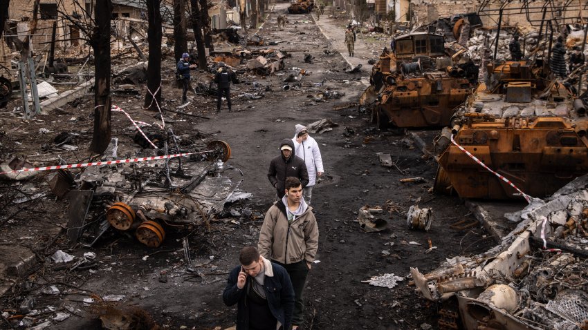 People walk through debris and destroyed Russian military vehicles, April 6, 2022, in Bucha, Ukraine. The Ukrainian government has accused Russian forces of committing a "deliberate massacre" as they occupied and eventually retreated from Bucha, northwest of Kyiv. Hundreds of bodies have been found in the days since Ukrainian forces regained control of the town.