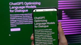 A person uses a mobile phone and computer to access the ChatGPT of the OpenAI website in Shanghai, China, February 18, 2023.