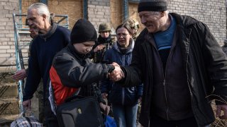 Myroslav shakes hand with his neighbor during an evacuation by Ukrainian police, in Avdiivka, Ukraine, March 7, 2023. For months, authorities have been urging civilians in areas near the fighting in eastern Ukraine to evacuate to safer parts of the country.