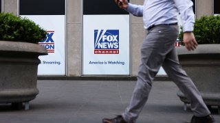 A person walks by Fox News signage posted on the News Corporation building in New York City, April 12, 2023