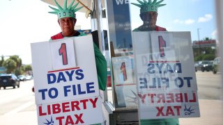 Gereon Moreno holds a sign indicating that there is one day left to file taxes as he stands in front of a Liberty Tax Service office in Miami, Florida, on April 17, 2023.