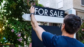 Close-up rear view of real estate agent adjusting for sign in front yard of house