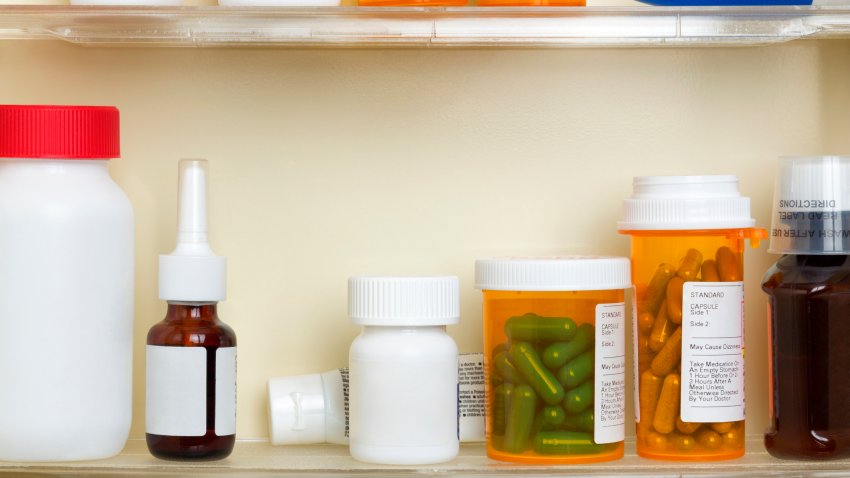 Several containers of over the counter and prescription medications on the shelves of a 1960’s medicine cabinet.