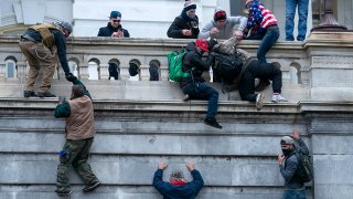 FILE - Rioters loyal to Donald Trump climb the west wall of the the U.S. Capitol, Jan. 6, 2021, in Washington.