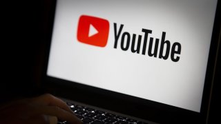 YouTube logo displayed on screen of a laptop as a person types on keyboard in Ankara, Turkey on July 18, 2018.