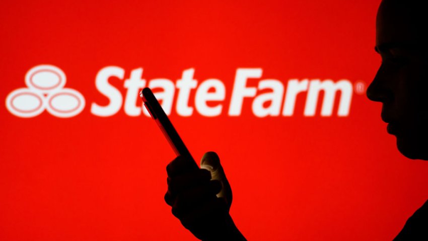 BRAZIL – 2022/06/28: In this photo illustration, the State Farm logo is seen in the background of a silhouetted woman holding a mobile phone.