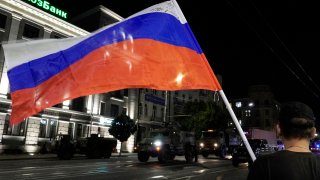 A man waves the Russian national flag as the members of Wagner group prepare to pull out from the headquarters of the Southern Military District to return to their base in Rostov-on-Don late on June 24, 2023. 