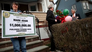 Sara Adair shows off the oversized check for $1 million her husband Mark received from the Publishers Clearing House Prize Patrol in South Boston, Massachusetts, on April 1, 2022.