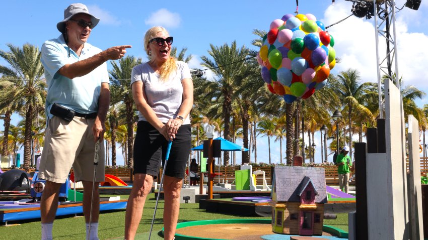 A couple plays a hole based on the movie UP at a Pixar Putt course.