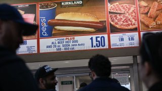 Customers wait in line to order below signage for the Costco Kirkland Signature $1.50 hot dog and soda combo, which has maintained the same price since 1985 despite consumer price increases and inflation, at the food court outside a Costco Wholesale Corp. store on June 14, 2022 in Hawthorne, California. (Photo by Patrick T. FALLON / AFP) (Photo by PATRICK T. FALLON/AFP via Getty Images)