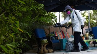 Barrington Sanders, a Miami-Dade Mosquito Control Inspector, sprays a pesticide to kill adult mosquitos on June 29, 2023 in Miami, Florida.
