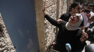 Nora Ghaith-Sub Laban touches the door to the home her family was evicted from to make way for Israeli settlers in Jerusalem’s Old City, Tuesday, July 11, 2023. As the last remaining Palestinians in a building filled with settlers, the Ghaith-Sub Labans have battled Israeli attempts to evict them from their Old City home for over 45 years. Settlers claim the family are squatters who had been living in an apartment formerly owned by Jews. (AP Photo/Mahmoud Illean)