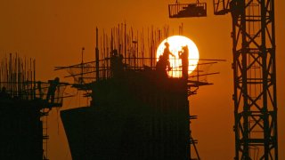 Chinese laborers working at a construction site at sunset in Chongqing, China.