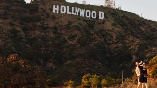 People take selfies beneath the Hollywood sign as the WGA (Writers Guild of America) strike continues on July 12, 2023 in Los Angeles, California.