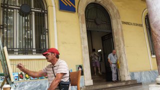 A customer exits a Piraeus Bank SA bank branch in Thessaloniki, Greece.