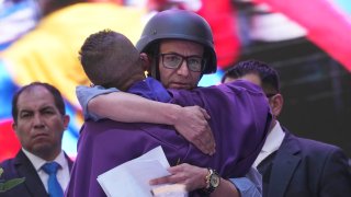 Wearing a bulletproof vest and ballistic helmet, presidential hopeful Christian Zurita, for “Movimiento Construye,” who was named to replace the recently slain Fernando Villavicencio, is embraced by a Catholic priest during a Mass prior to his closing campaign rally in Quito, Ecuador, Thursday, Aug. 17, 2023. The upcoming snap election set for Aug. 20 was called after President Guillermo Lasso dissolved the National Assembly by decree in May, to avoid being impeached. (AP Photo/Dolores Ochoa)