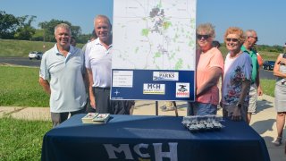 Officials pose with a map of the proposed Midwest Interstate Trail, which would connect Illinois and Wisconsin.