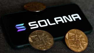 The Solana logo on a phone screen and representation of cryptocurrencies are seen in this photo taken in Krakow, Poland, Aug. 21, 2021.