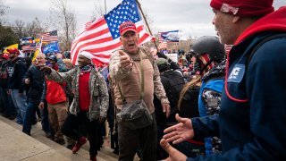 Ray Epps, in the red Trump hat, center, gestures to others as people gather on the West Front of the U.S. Capitol in Washington, D.C., Jan. 6, 2021.
