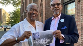 Chester Deanes, left, and Ben Phillips hold a photo of the former Pruitt-Igoe housing development in St. Louis, where they lived growing up on Sept. 7, 2023. The Army sprayed a potential carcinogen from the tops of buildings and from station wagons in the area around Pruitt-Igoe in the 1950s and 1960s as part of secret Cold War-era testing. Deanes and Phillips are leading an effort to get government compensation.  (AP Photo/Jim Salter)