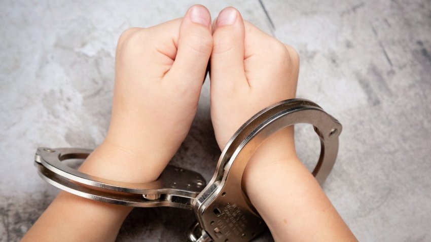 Picture of young child’s hands in hand cuffs