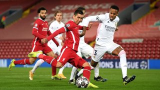 Roberto Firmino of Liverpool shoots whilst under pressure from Eder Militao of Real Madrid during the UEFA Champions League Quarter Final Second Leg match between Liverpool FC and Real Madrid at Anfield on April 14, 2021 in Liverpool, England.